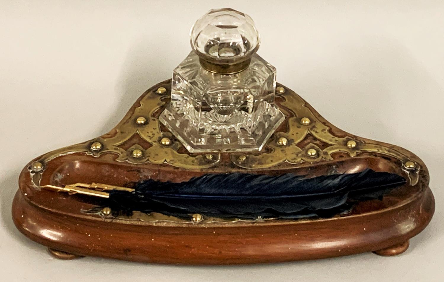 A Victorian mahogany and brass desk stand, with an octagonal glass inkwell, raised on three ball
