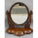 A Victorian swing dressing table mirror, the oval glass with carved supports, the base with hinged