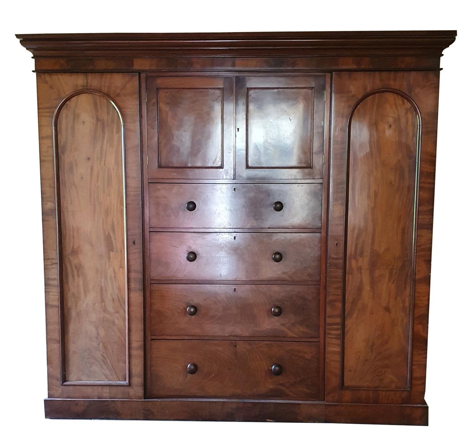 A 19th century mahogany wardrobe, the central cupboard over four graduated drawers, the right