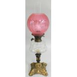 A late Victorian brass and glass oil lamp, with cut clear glass reservoir, globular acid etched ruby