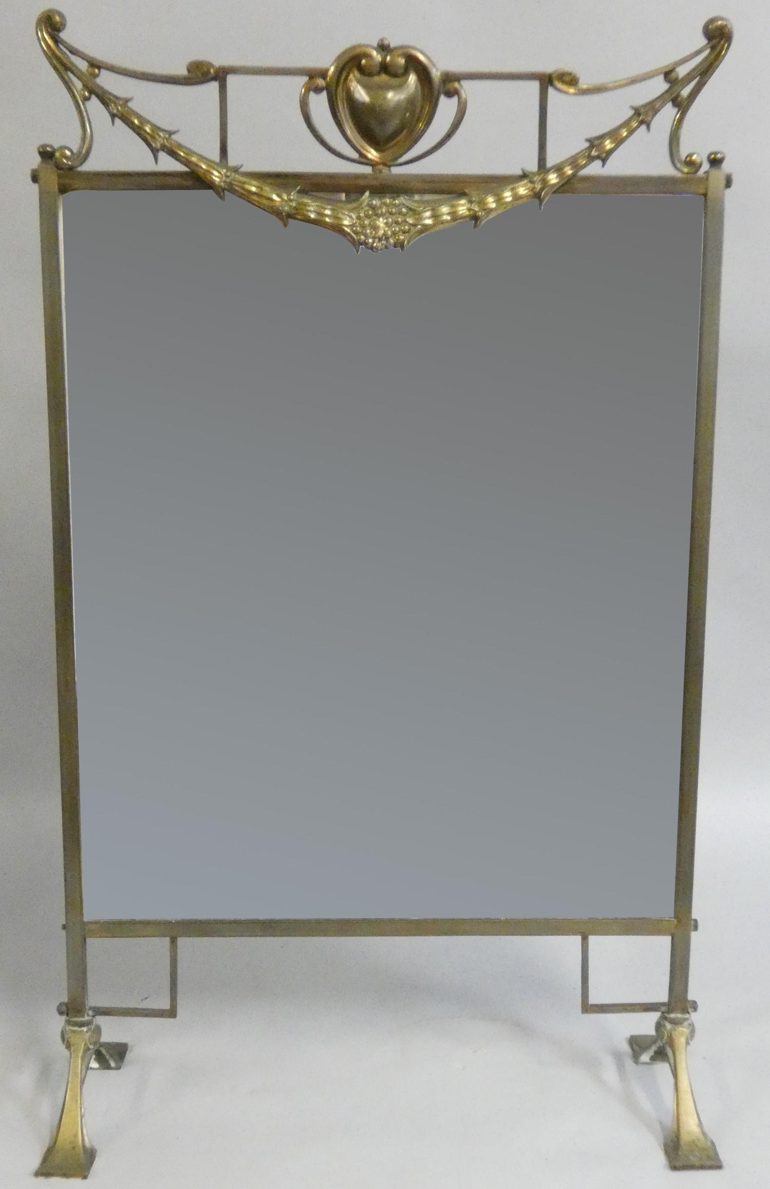 An Art Nouveau brass framed mirrored firescreen, 81cm.