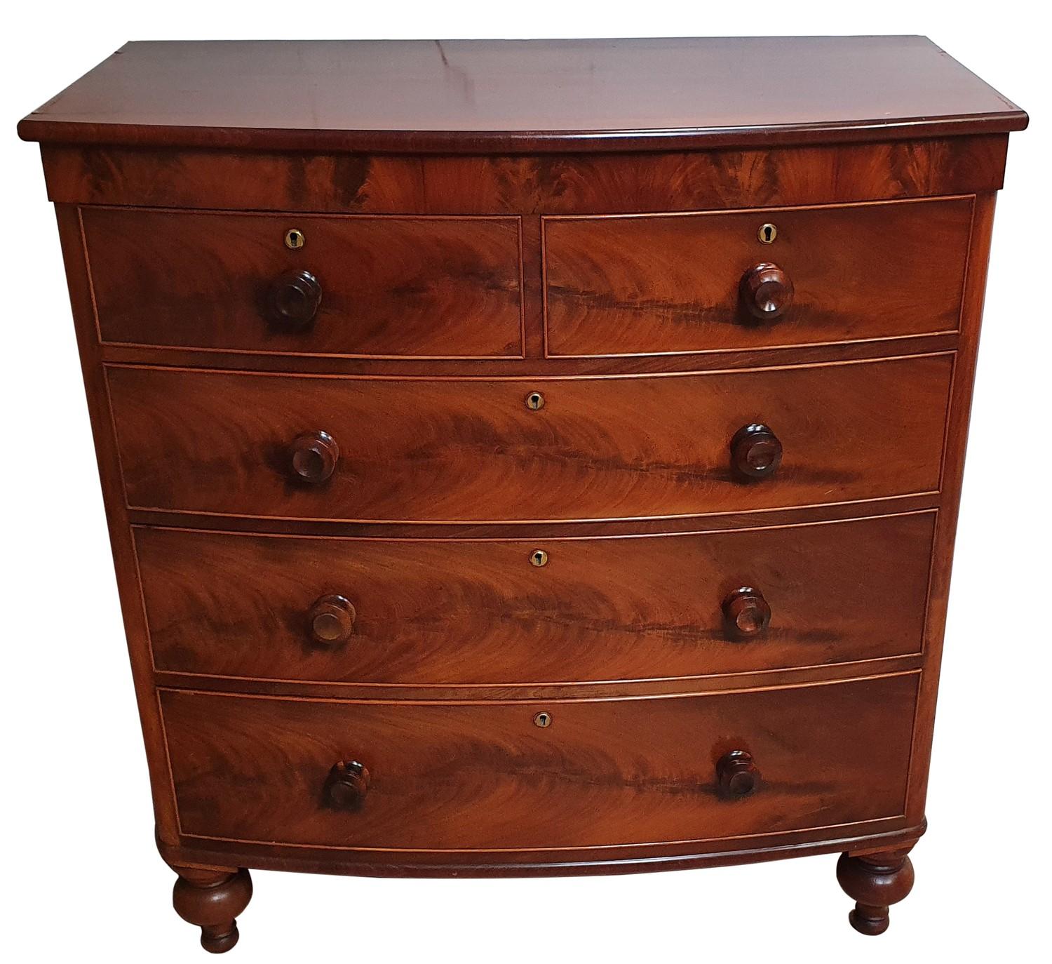 A Victorian mahogany bow front chest of two short over three long drawers, bun handles, raised on