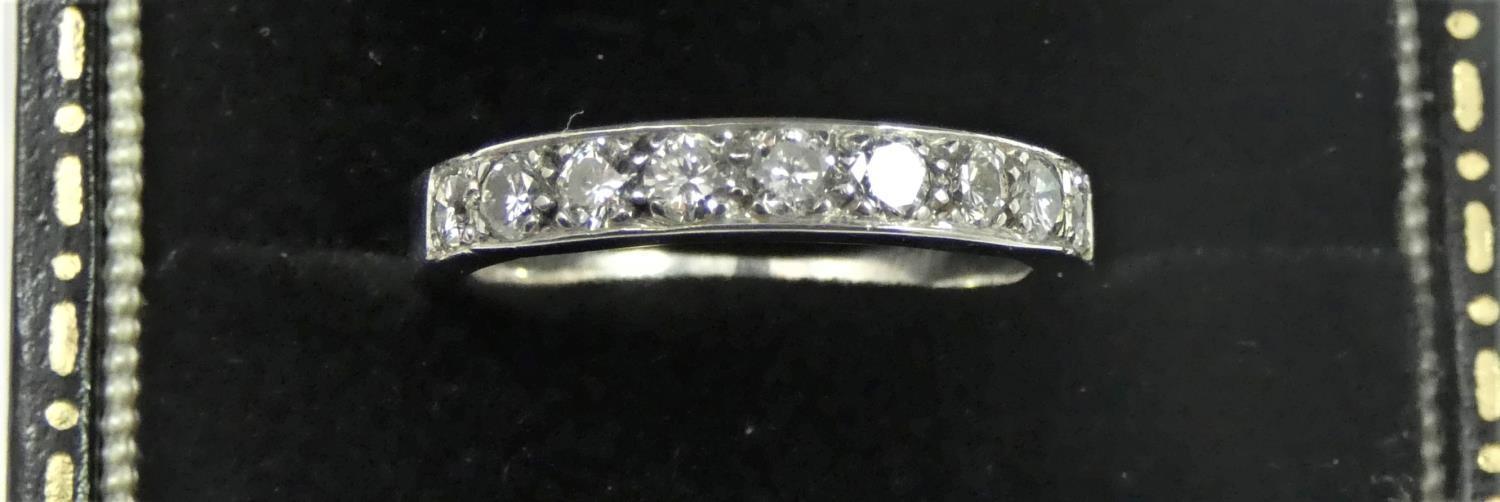 A white metal, probably platinum and diamond half eternity ring, set with nine brilliant cut stones,