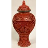 A Chinese cinnabar lidded vase, carved with two floral panels, 17 cm.