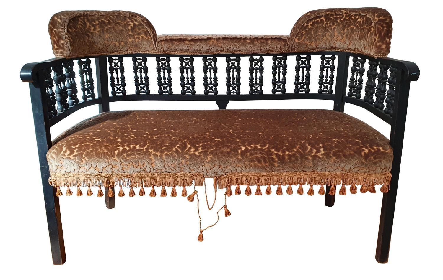 An Edwardian ebonised beech sofa, the upper section with turned bobbin supports, upholstered seat,