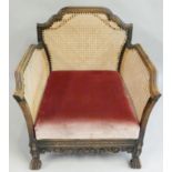 An Edwardian stained beech and cane bergere armchair, with carved base and lift out seat,