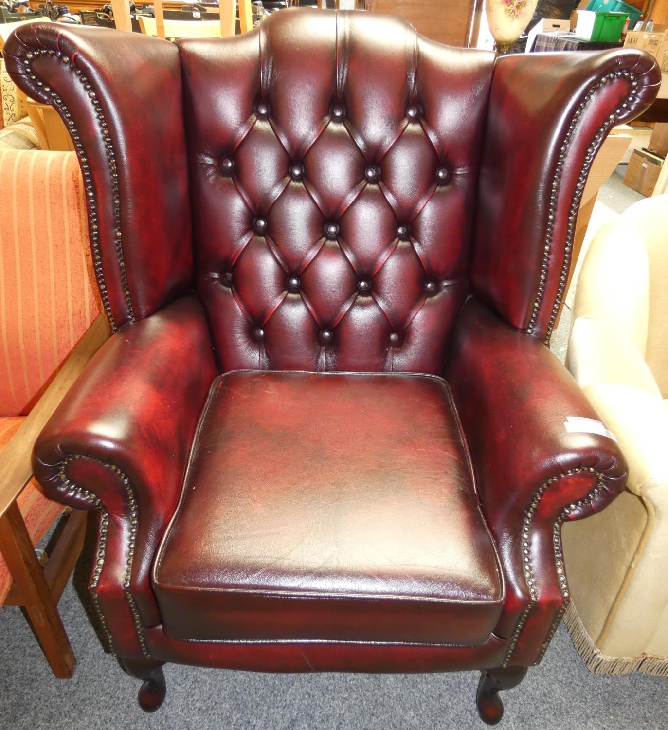 A Queen Anne style high back wing chair manufactured in the United Kingdom, antique oxblood