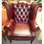 A Queen Anne style high back wing chair manufactured in the United Kingdom, antique oxblood