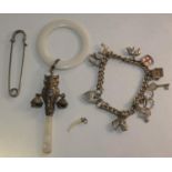 A silver charm bracelet, a silver and mother of pearl rattle, Birmingham 1959, and a nappy pin (3).