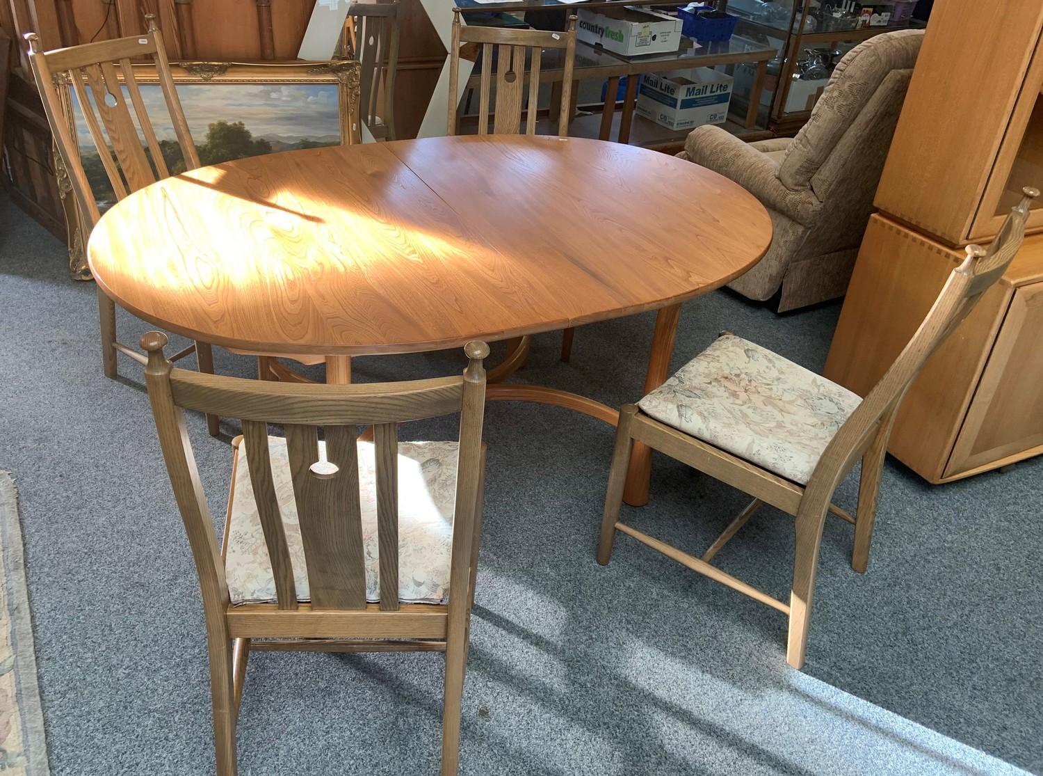 An Ercol medium oak oval extending dining table (162 cm long- 212 cm extended) together with a set