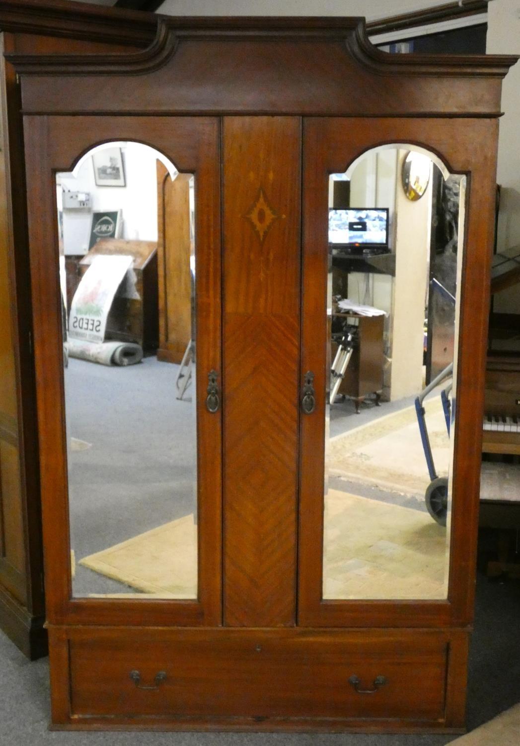 A mahogany double wardrobe with mirrored doors over single base drawer, both sides providing full