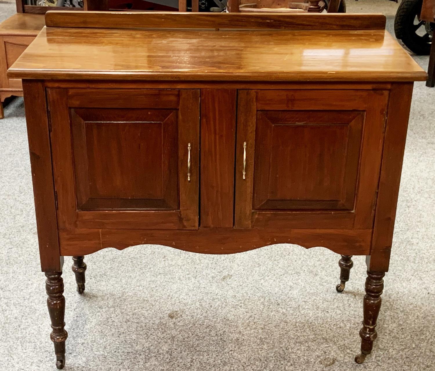 A stained wood washstand, raised on brass castors.