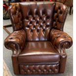 A brown leather button back wing armchair (matches lot 288).