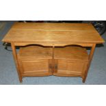 An Edwardian oak table, the rectangular top 109 x 52 cm over open shelf above twin canted cupboards.