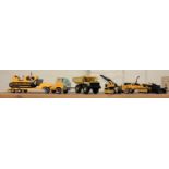 A collection of Tonka toys, including a transporter, truck, bulldozer, two diggers and a crane,