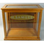 An oak glass fronted display cabinet by Griffin & George Ltd, painted 'H. Samuel Clock Making &