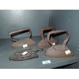 A selection of cast flat stove irons and stand