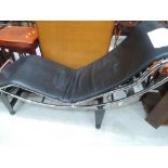 A modernist designer chrome and black leather chaise longue, after Le Corbusier