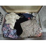 A vintage suitcase containing a quantity of ladies modern and retro skirts, blouses dresses and