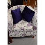 A modern tub armchair and two purple scatter cushions