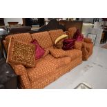 A modern lounge suite having russet ground, 3 seater settee, chair and ottoman style footstool