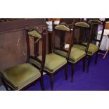 A set of four late Victorian mahogany salon chairs having panel and slat backs with later moss green
