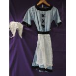 A traditional Dutch style childrens outfit, comprising of blue gingham dress, apron and hat, appears