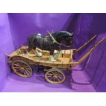 A hand made wooden four wheel cart being pulled by a ceramic shire horse with harness