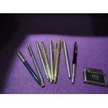 A selection of eight ballpoint pens and a vintage cigarette lighter. Pens include Parker gold