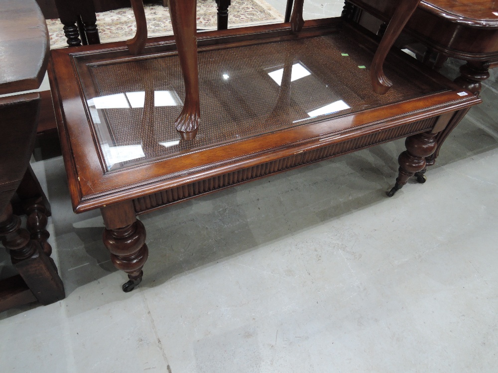 A modern mahogany frame coffee table having inset glass and rattan top on guard legs