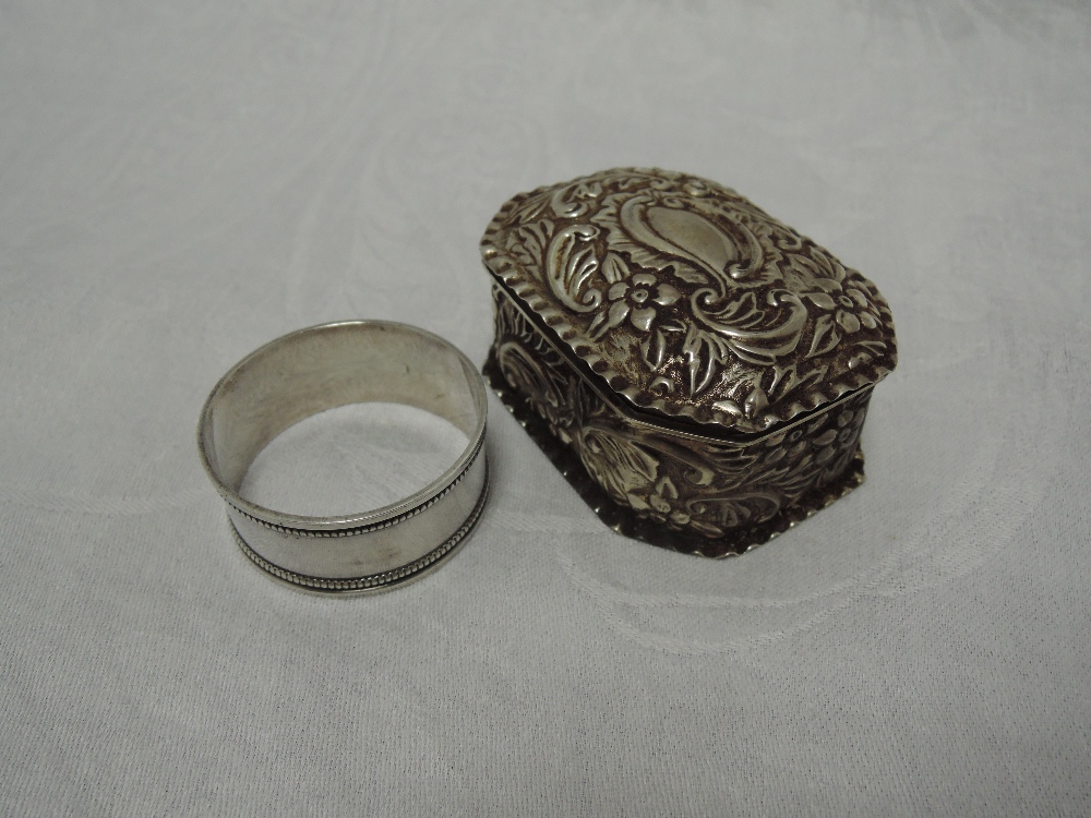 A Victorian silver trinket box having hinged lid, extensive repousse floral decoration and frilled