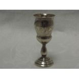 A small Russian silver vodka goblet having scenic engraving with baluster stem to stepped circular