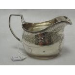 A Georgian silver cream jug of helmet form having bright cut decoration and monogram to cartouche,