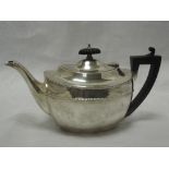 A silver tea pot of plain oval form having moulded decoration to rim, flush lid and hard wood