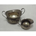 An Edwardian silver sugar bowl and cream jug of plain form having loop handles, Birmingham 1907,