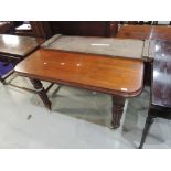 A late Victorian mahogany wind out dining table on reeded fluted legs with extra leaf