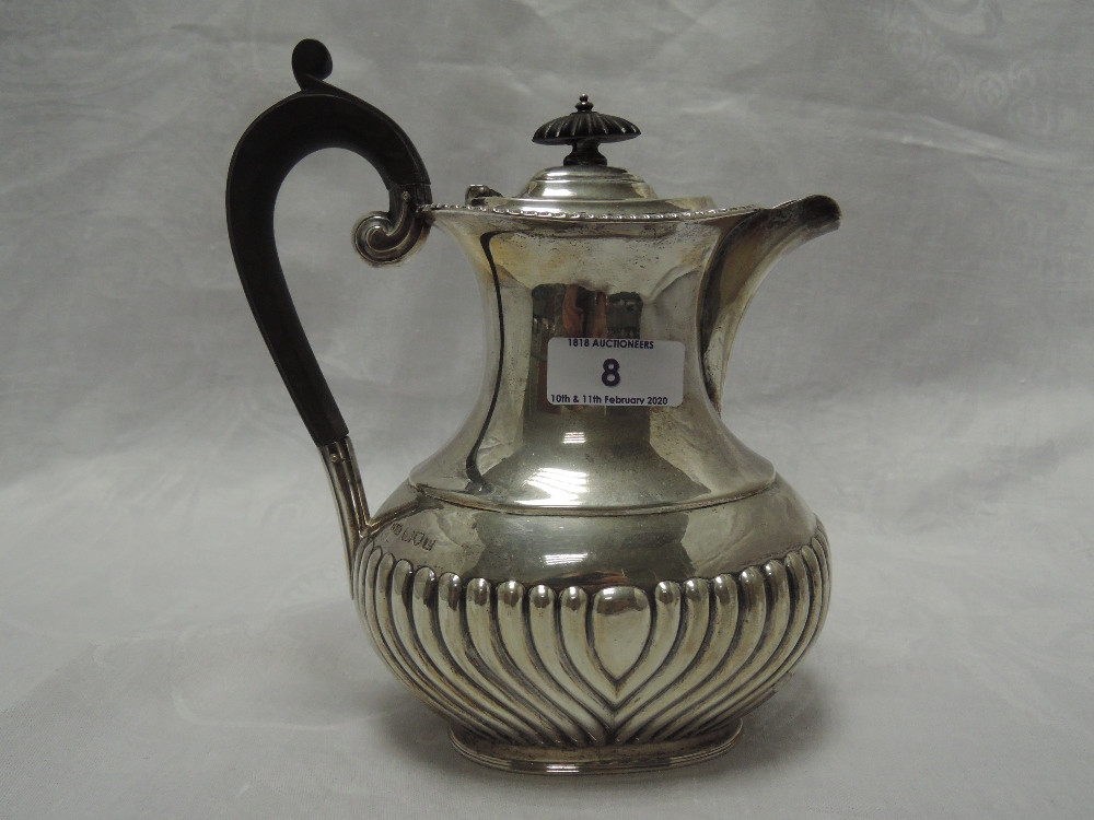 A silver hot water pot of oval baluster form having gadrooned decoration and hard wood handle,