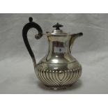 A silver hot water pot of oval baluster form having gadrooned decoration and hard wood handle,