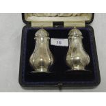 A cased pair of Edwardian silver pepperettes of plain facetted baluster form, Birmingham 1906,