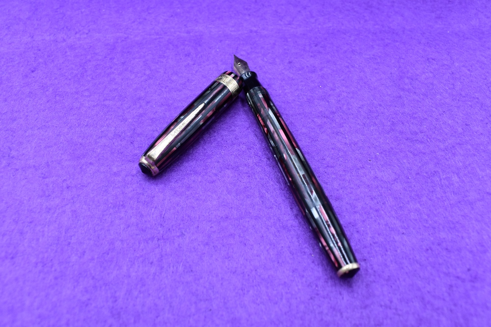 A Parker Duofold Vacumatic in pink, silver and black straited with broad decorated band to cap.