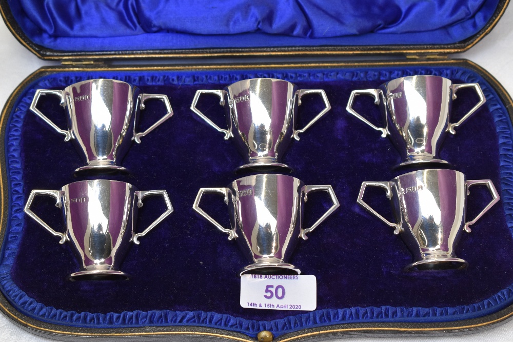 A cased set of six Edwardian silver tot glasses of two handled trophy form, London 1904, Wakeley &