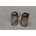 A pair of Edwardian silver pepperettes having domed lids, loop handles and plain cartouches,