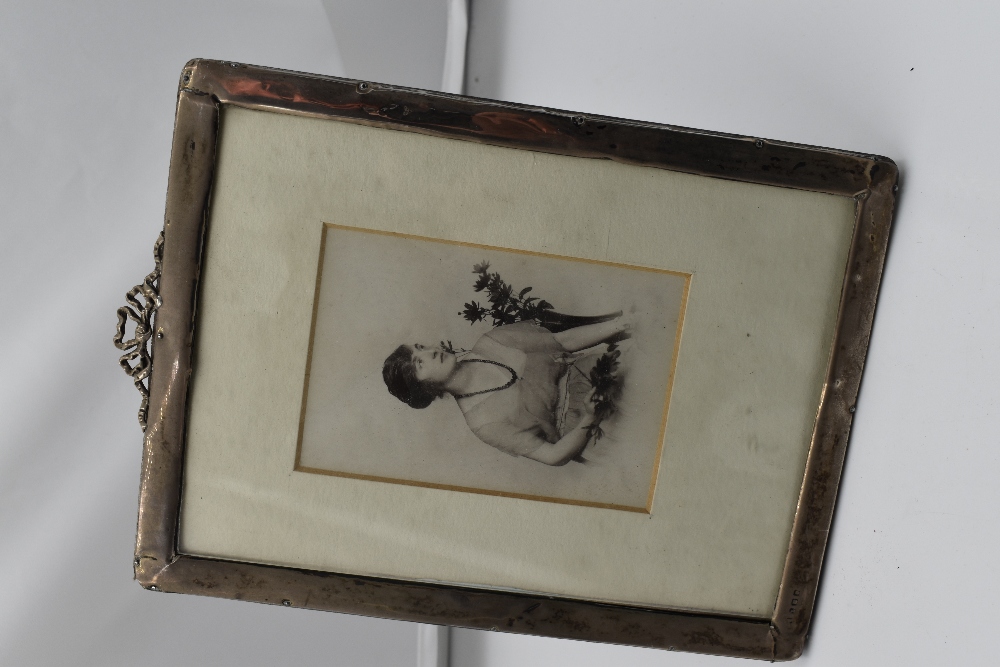 A silver photograph frame of plain rectangular form having moulded ribbon detail to top and velvet