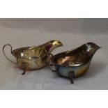 A pair of silver sauce boats of plain form having shaped rims, loop handles and trefoil paw feet,