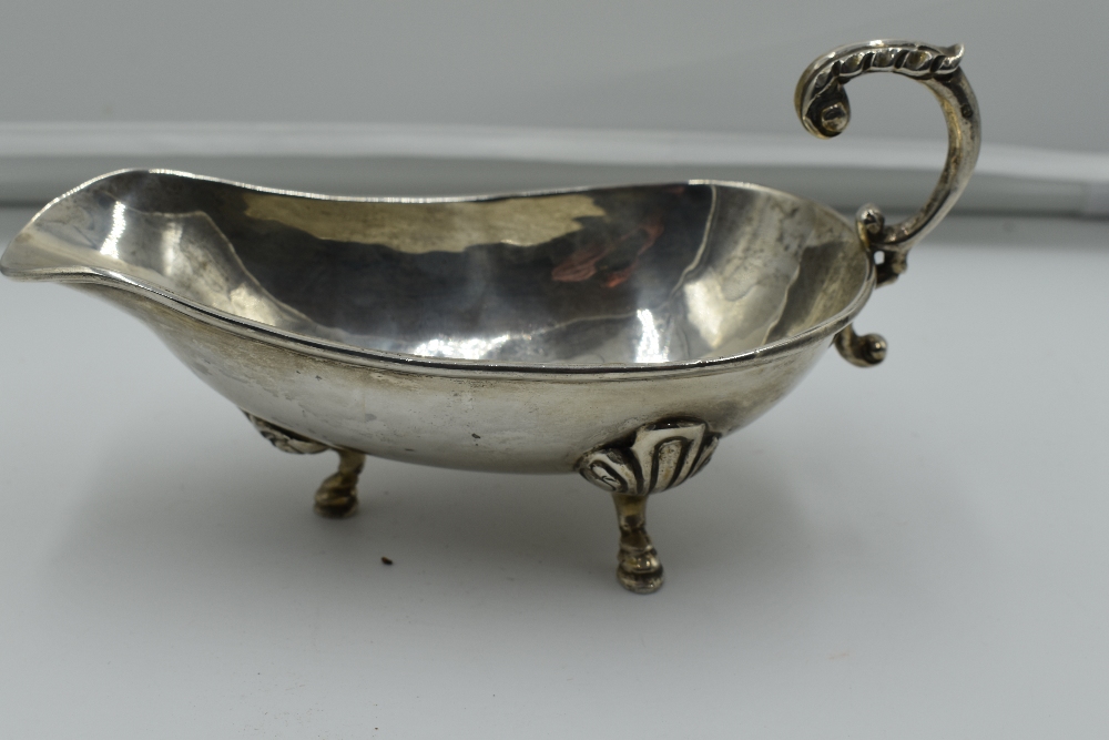 A white metal sauce boat stamped sterling 925, having moulded loop handle and trefoil hoof feet