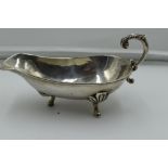 A white metal sauce boat stamped sterling 925, having moulded loop handle and trefoil hoof feet