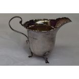 A silver cream jug of plain helmet form having shaped rim and trefoil paw feet, Birmingham 1927,