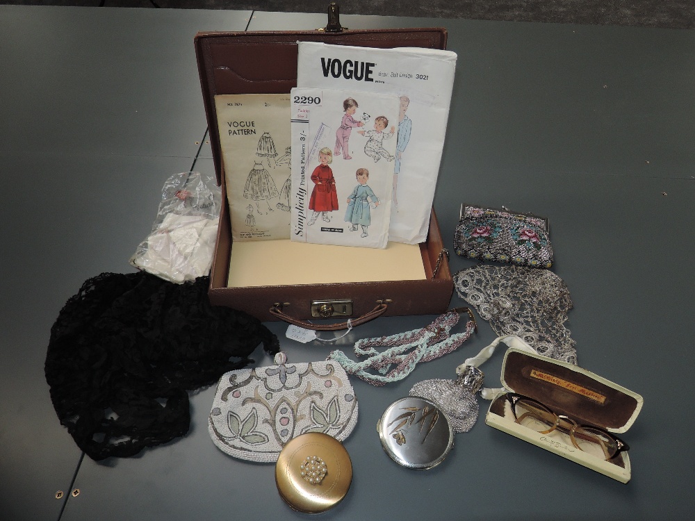 A Cheney writing case containing a set of 1950s glasses, two compacts, three dress patterns, two