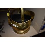 A lovely vintage hammered brass coal scuttle having integrated wooden handled shovel to side.