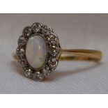 A lady's dress ring having an opal and diamond cluster in a pave mount on a yellow metal loop